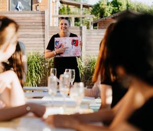 Professionelle Anleitung im Malworkshop Kursleiterin erklärt Teilnehmenden die nächsten Schritte im abstrakten Malworkshop