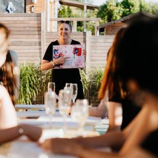 Professionelle Anleitung im Malworkshop Kursleiterin erklärt Teilnehmenden die nächsten Schritte im abstrakten Malworkshop