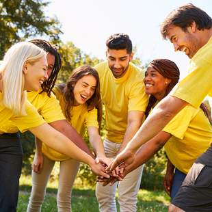 Eine Gruppe von Menschen mit gelben T-Shirts steht zusammen und legt die Hände zusammen