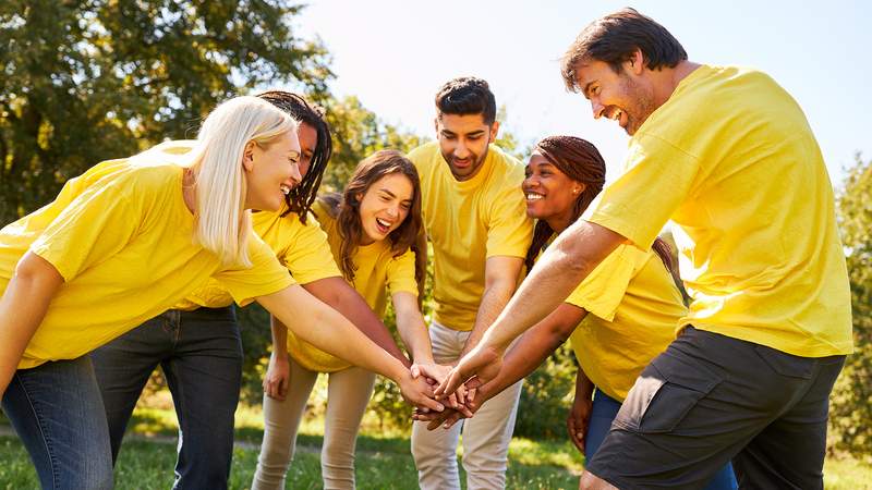 Eine Gruppe von Menschen mit gelben T-Shirts steht zusammen und legt die Hände zusammen