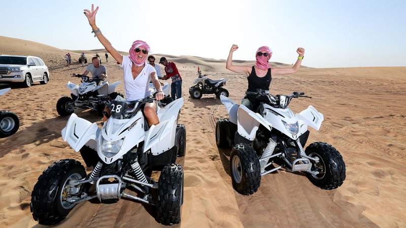 Zwei Frauen sitzen auf einem Dune Buggy und freuen sich über die tolle Buggy Dünen Tour mitten durch die Wüste.