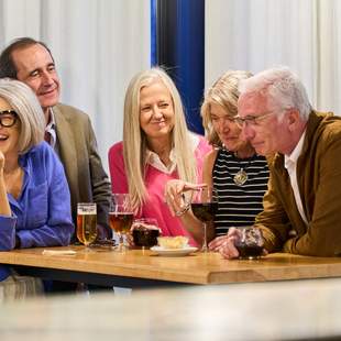Teamchallenge Gruppe von Menschen, die um einen Tisch stehen. Lachend eine Aufgabe lösen