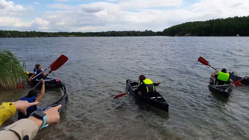 Mehrere Personen stechen mit einem selbstgebauten Kanu in die See