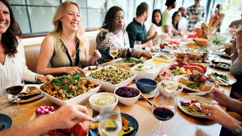 Menschen essen gemeinsam an einem langen Tisch mit vielen Speisen