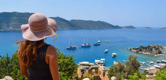 Dame mit Hut schaut auf das türkische Meer mit Booten