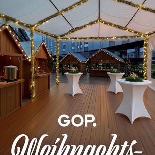 GOP Weihnachtsmarkt Weihnachtlich geschmücktes Zelt mit Stehtischen und Weihnachtsmarkthütten und dem Schriftzug "GOP Weihnachtsmarkt".