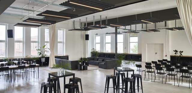 Bestuhlungsbeispiel Lounge Links stehen Tische mit Stühlen im Hintergrund, mittig vorne im Bild sieht man Stehtiche mit hohen. Hockern und rechts hinten sieht man eine Reihenbestuhlung.